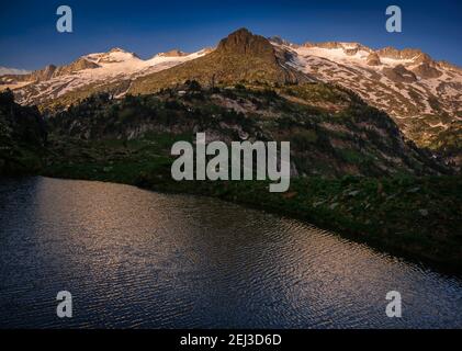 Aneto summit and the Maladeta massif viewed from Ibón Superior de Villamuerta in a summer sunrise (Benasque valley, Pyrenees, Spain) Stock Photo