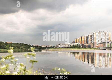 The coast of the Gulf of Finland with modern buildings. Island and parkland on the horizon. Stock Photo