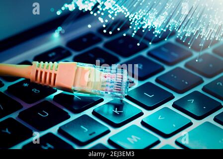 Internet cable, RJ-45 plug on laptop keyboard. High speed fiber optic internet concept Stock Photo