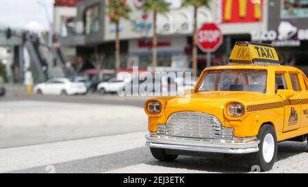 LAS VEGAS, NEVADA USA - 7 MAR 2020: Yellow vacant mini taxi cab close up on Harmon avenue corner. Small retro car model. Little iconic auto toy as sym Stock Photo