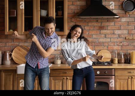Overjoyed young couple dancing in modern kitchen, having fun Stock Photo