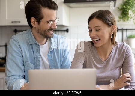 Happy millennial couple have fun using laptop at home Stock Photo