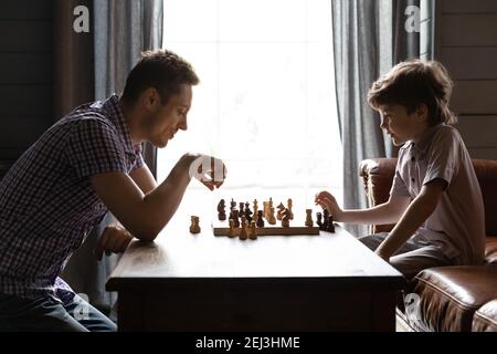 Side view father and little son playing chess at home Stock Photo