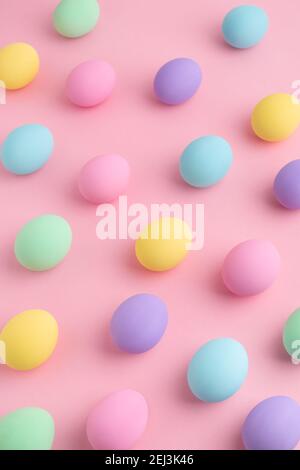 Pastel colored Easter eggs scattered on pink background. Easter Day colorful pattern, abstract flat lay. Stock Photo