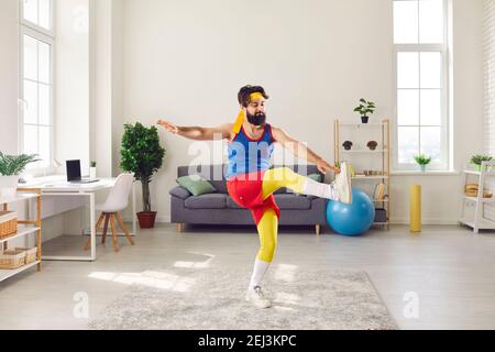 Clumsy young man doing front leg raise toe tap gymnastic exercise in his living-room Stock Photo