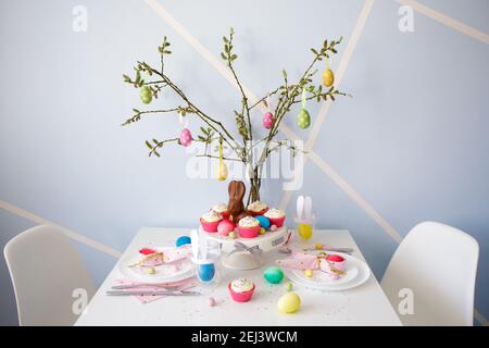 easter concept - decorated table with cupcakes, colorful painted eggs and bunnies Stock Photo