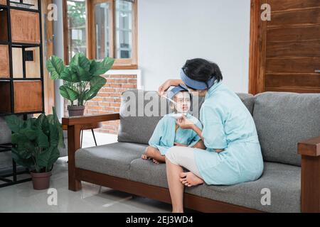 cute little girl face when a mother smears facial cream with a brush sitting a couch at living room Stock Photo