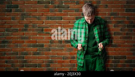young male hipster tight the shoelace belt,trendy fashion idea isolated against the wall Stock Photo