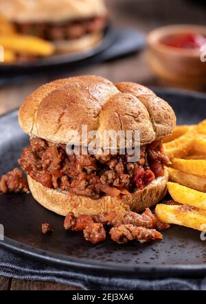 Sloppy joe sandwich and french fries on a black plate Stock Photo