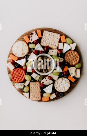 Cheese platter with different type of cheese. Camembert, cheddar, goat chesse, bleu, grapes and olive with crackers. Healthy vegetarian food idea. Stock Photo