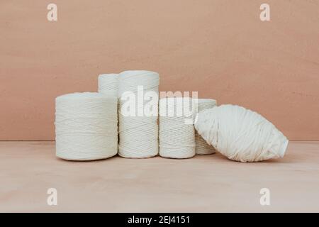 Set of white knitting yarn spool on beige background. Different size cotton threads. Stock Photo