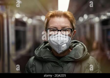 Portrait mature woman in respirator mask  traveling in subway train. Concept of new life reality during COVID 19 pandemic Stock Photo