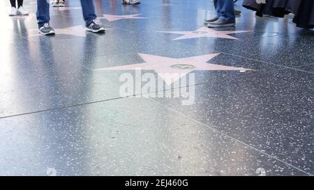 LOS ANGELES, CALIFORNIA, USA - 7 NOV 2019: Walk of fame promenade on Hollywood boulevard in LA. Pedastrians walking near celebrity stars on asphalt. W Stock Photo