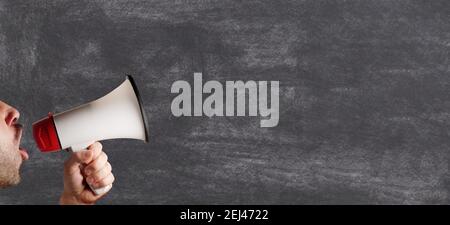megaphone speaking announcing man against blank blackboard chalkboard copy space Stock Photo