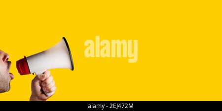 megaphone speaking announcing against isolated on yellow solid background Stock Photo