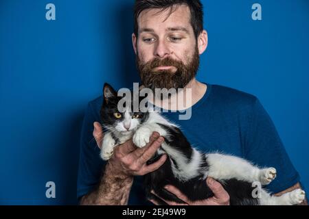 Man in blue  t-shirt holding black and white cute cat Stock Photo