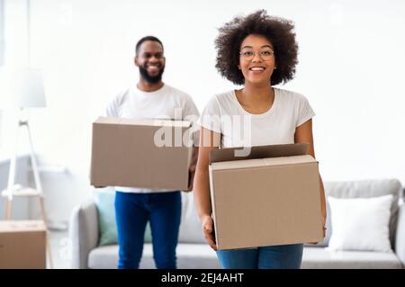 Black Couple Moving Carrying Packed Cardboard Boxes Into New Home Stock Photo