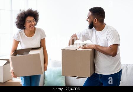 Joyful African Couple Laughing Carrying Moving Boxes Together Indoors Stock Photo