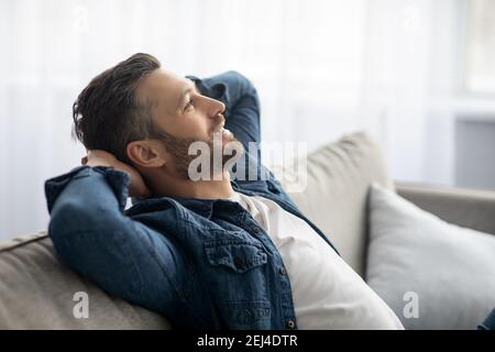 Handsome middle-aged man relaxing on sofa at home Stock Photo