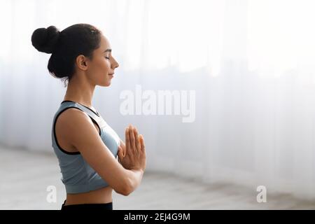 Side view of young brunette woman meditating at home Stock Photo