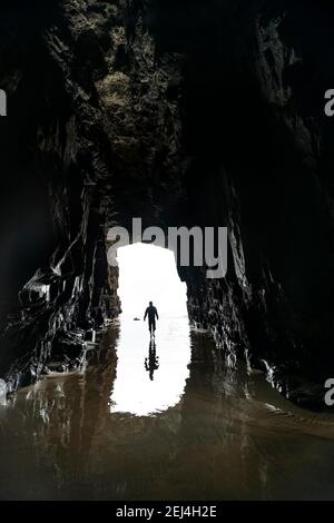 Silhouette of a person in front of cave exit in backlight, cave washed out by the sea, Cathedral Cave, Waipati Beach, The Catlins, Southland, South Stock Photo