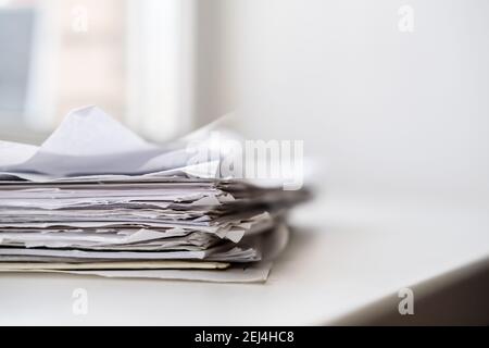 A stack of paper for writing and notebooks on a white windowsill in natural light from the window.  Stock Photo
