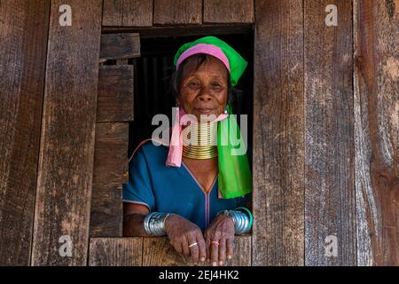 Padaung, giraffe, woman standing in a window frame of her house, Panpet, Loikaw area, Kayah state, Myanmar Stock Photo