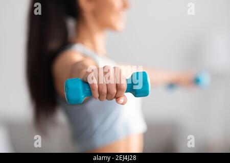 Selective focus on dumbbell in sporty woman hand Stock Photo