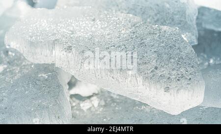 Transparent shining clear ice icicles close-up sparkling on frozen wild lake shore in sunset light. Cold winter nature background Stock Photo