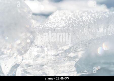 Transparent shining clear ice icicles close-up sparkling on frozen wild lake shore in sunset light. Cold winter nature background Stock Photo