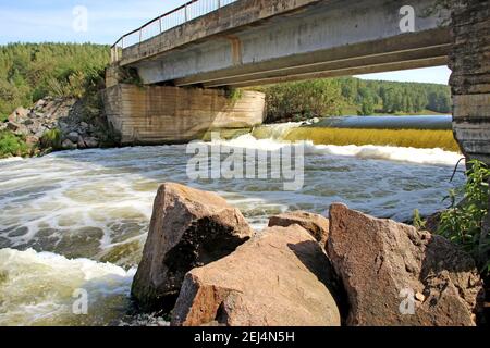 The mountain river flows under the bridge bubbling and foaming. Stock Photo