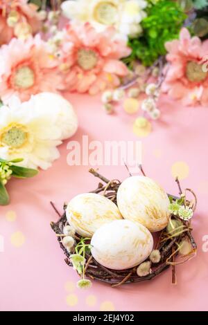 Easter floral background. Spring flowers gerbera with easter eggs on pink background. Stock Photo