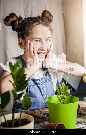 cute cheerful caucasian girl is laughing while gardening. spring flower planting with children. happy moments. front view. close-up. Stock Photo