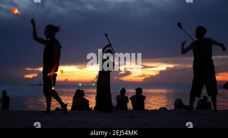 PHANGAN, THAILAND - 23 MARCH 2019 Zen Beach. Silhouettes of performers on beach during sunset. Silhouettes of young anonymous entertainers rehearsing Stock Photo
