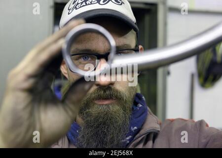 worker looking through pipe working in a bicycle repair shop Stock Photo