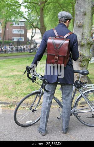 Handsome caucasian man holding his bike in Park wearing smart casual attire with leather back pack in London , Uk Stock Photo