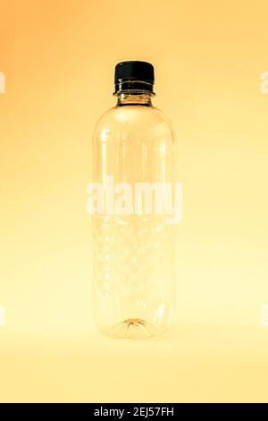An empty generic single use plastic water bottle on a yellow background, no label Stock Photo