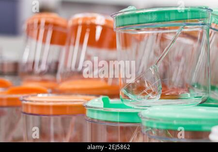 Photo of different colored plastic boxes and containers standing on shelf in store. Stock Photo