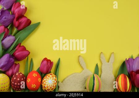 tulips, painted eggs and chick shaped cookies on yellow background Stock Photo