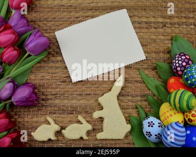 tulips, painted eggs and bunny shaped cookies on brown background Stock Photo