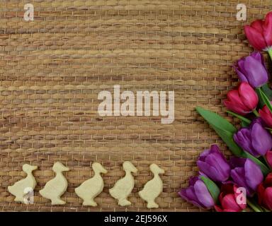 tulips, painted eggs and chick shaped cookies on brown background Stock Photo