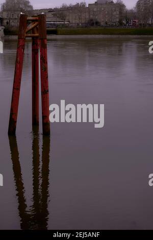 Old remains of bridge structure protruding up from and reflected on the River Thames London next to grovsenor railway bridge Stock Photo