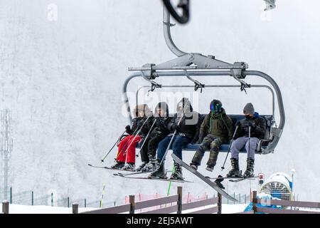 Tufandag, Gabala - Azerbaijan: 30 January 2021. Snowfall. Happy friends on ski lift chair enjoying winter ski vacations in mountains. Stock Photo