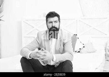 On wedding anniversary. Bearded man in wedding style sit on bed. Hipster wait in wedding suite. Formalwear and party wear. Fashion and style. Wedding shop. Stock Photo