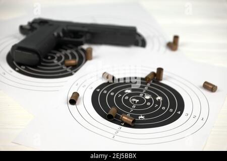 Gun and many bullets shooting targets on white table in shooting range polygon. Training for aiming and shooting accuracy Stock Photo