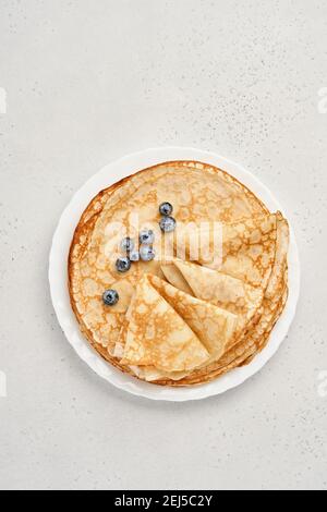 Thin pancakes, crepes or blini with berries in white plate. Top view. Pancake week. Shrovetide. Space for text.