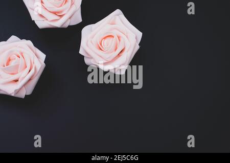A vtop view of three artificial rose buds on a black background Stock Photo