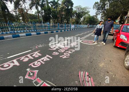 A couple walks past the road graffiti made at Rabindra sadan area on the occasion of International Mother Language Day.Road graffitis are made on the occasion of International mother language day in Kolkata. Stock Photo
