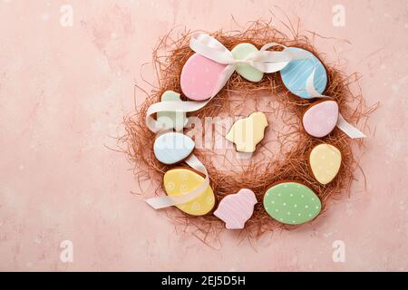 Easter eggs, cookie and colorful sweet made in shape of circle wreath on pink background. Minimal holiday concept with copy space for text. Flat lay p Stock Photo