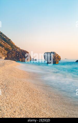 A vertical shot of a tropical sandy beach with lagoon smooth waves washing the shore Stock Photo